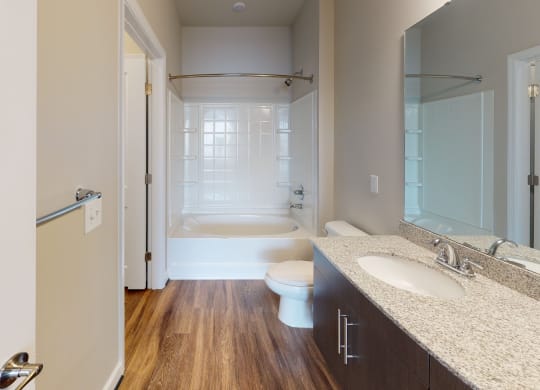 Bathroom with sink, toilet, shower and tub; dark cabinets, vinyl floors
