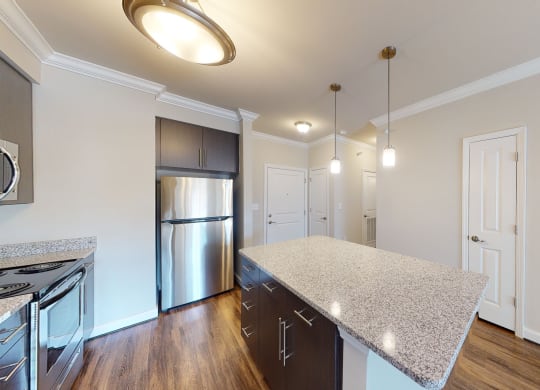 Kitchen with island, dark cabinets, vinyl floors and granite countertops