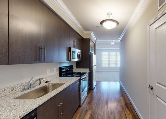 Kitchen with dark cabinets, granite countertops, vinyl wood plank floors; open to living room