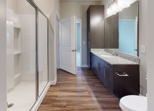 Bathroom with shower, dark cabinets, vinyl floors