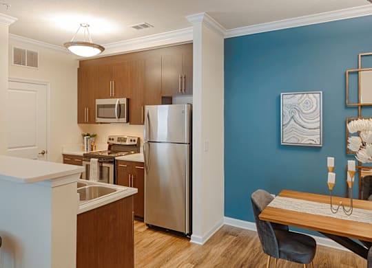 Dog-Friendly Luxury Apartments in Charlotte, North Carolina - Belmont at Tryon - Kitchen With Wood Cabinets, Stainless Steel Appliances, Double Sink, and Breakfast Bar.