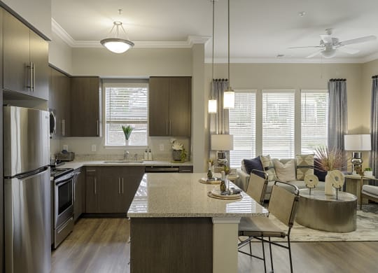 Kitchen with dark cabinets, granite countertops, vinyl wood plank floors; island; open to living room