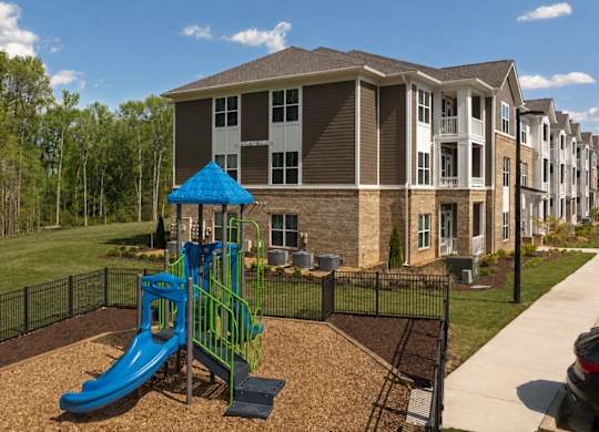 A playground with a blue slide in front of a building.