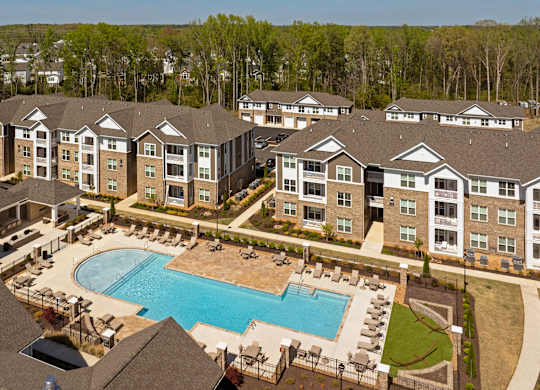 A large apartment complex with a swimming pool in the foreground.