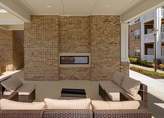 A patio with a couch, chair, and fireplace.