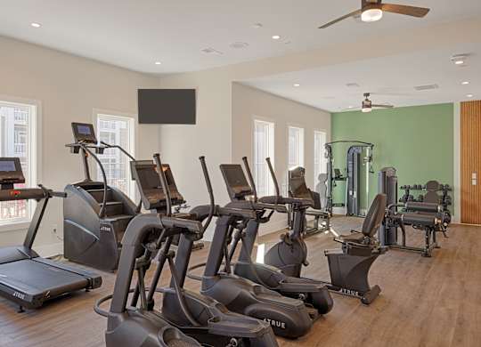 A gym with treadmills, elliptical machines, and a weight room.