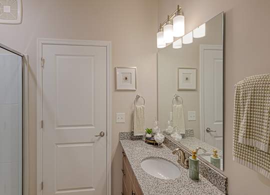 A bathroom with a sink, mirror, and towel rack.