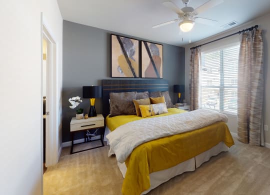 Bedroom with ceiling fan, carpet and door to bathroom