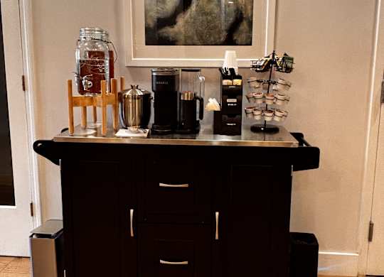 A black coffee cart with a variety of items on top of it.