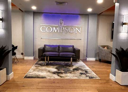 A Compson logo is displayed on a wall above a couch.