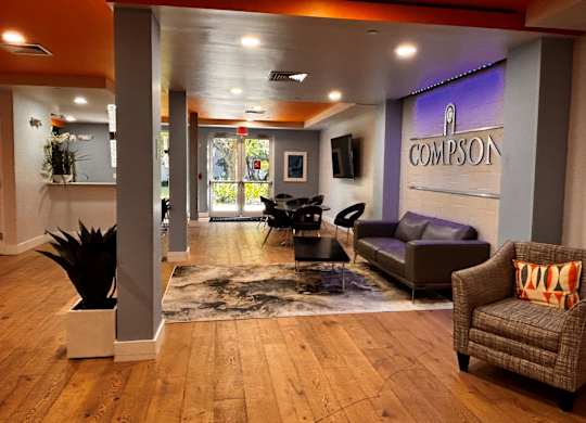 A lobby with a leather couch and a sign reading “Compson”.