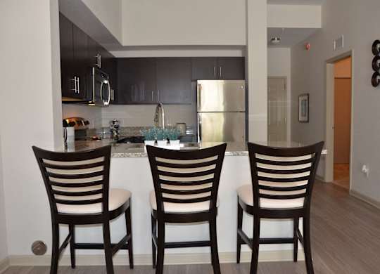 Three wooden chairs are placed in front of a kitchen island.