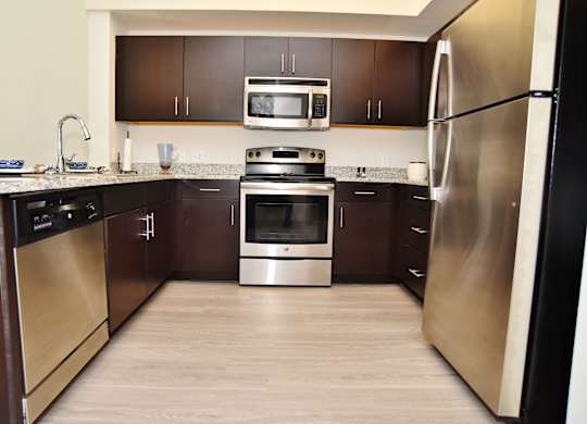 A modern kitchen with dark wood cabinets and stainless steel appliances.