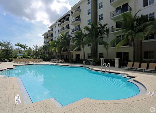 A swimming pool surrounded by palm trees and apartment buildings.