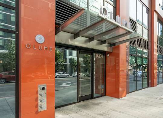 The entrance to a building with a glass door and a sign that reads "OLUME".