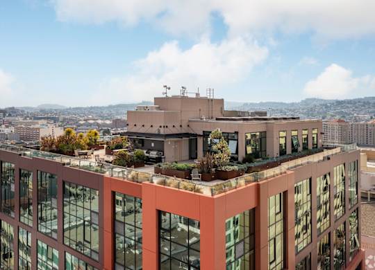 A modern building with a lot of windows and plants on the roof.