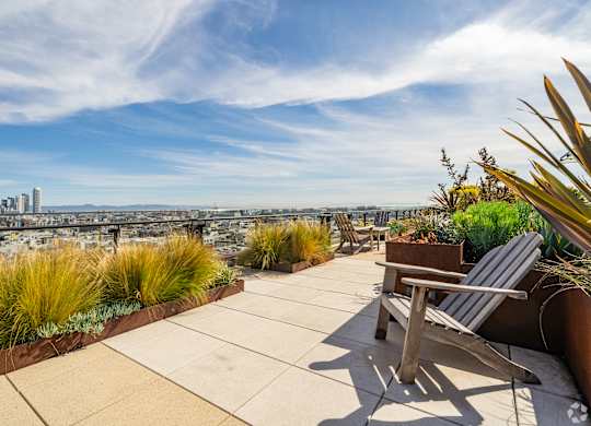 A rooftop patio with a chair and a view of the city.