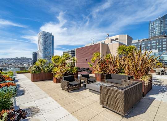 A rooftop patio with furniture and plants.
