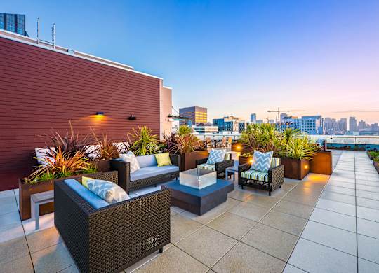 A rooftop patio with a couch, chairs, and plants.