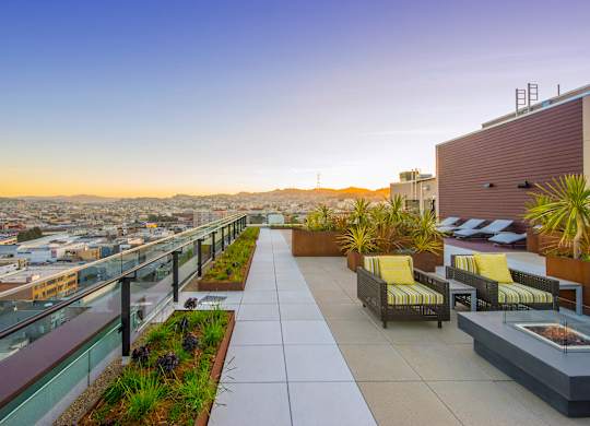 A rooftop patio with yellow chairs and plants.