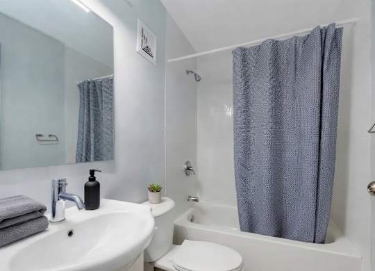 A white sink with a grey towel and a black soap dispenser on top of it.