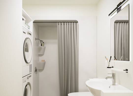 A white bathroom with a washer and dryer built into the wall.