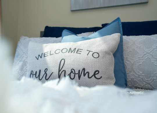 a pillow that says welcome to our home on a bed