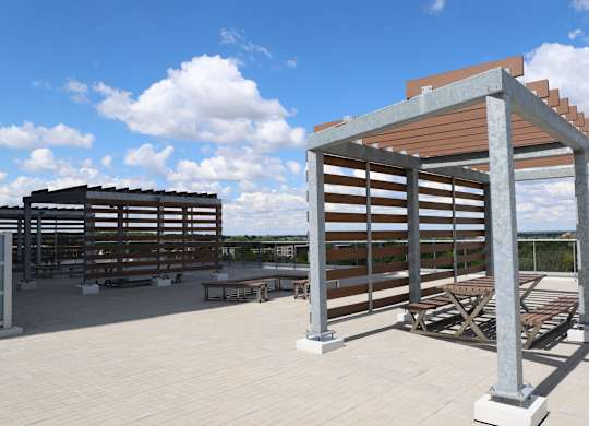 the roof terrace of the building has tables and chairs and awning