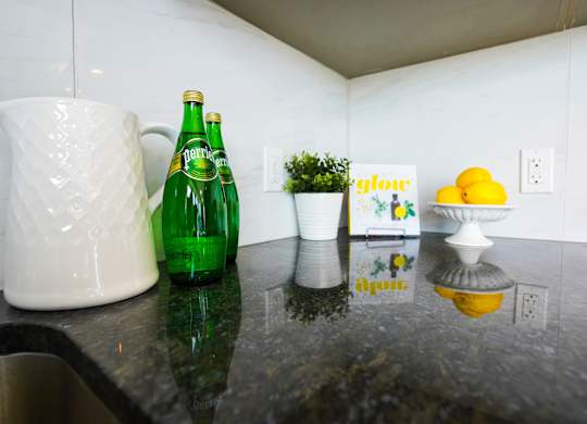 a kitchen counter with a green bottle and a white pitcher on it