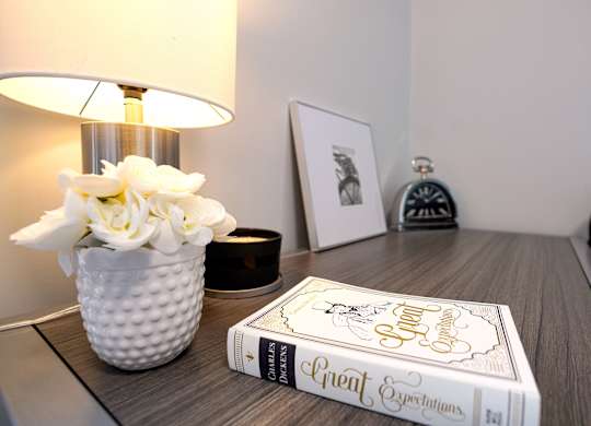 a desk with a book and a vase with flowers on it