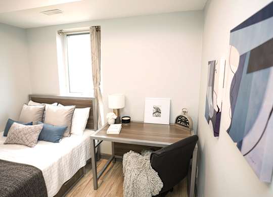a bedroom with a bed and a desk and a window