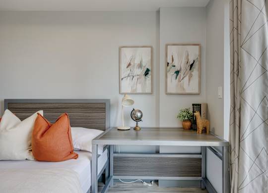 A bedroom with a bed, nightstand, and two framed pictures on the wall.