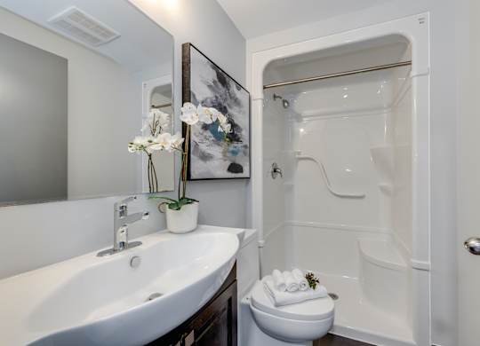 A white sink with a mirror above it and a white toilet in a bathroom.
