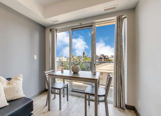 A dining room with a table and chairs and a view of the city.