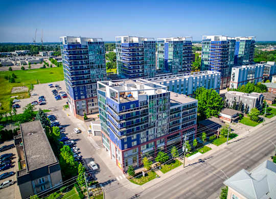 A modern multi-story building complex is surrounded by a parking lot and other buildings.
