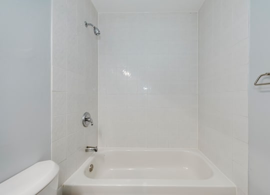 A white bathroom with a tub and toilet.