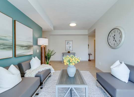 A living room with grey couches, a coffee table, and a large painting on the wall.