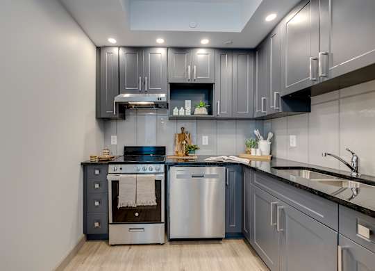 A modern kitchen with stainless steel appliances and grey cabinets.
