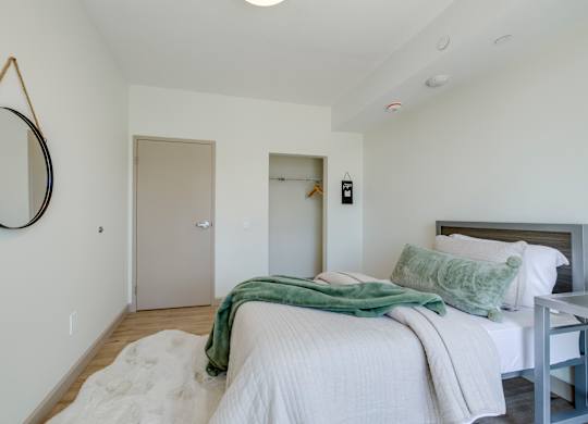 A bedroom with a bed, a mirror, and a door.