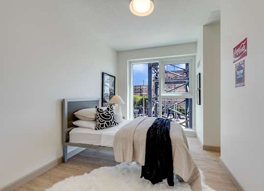 A bedroom with a bed and a window overlooking a city.