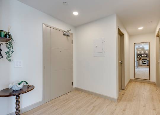 A hallway with a wooden floor and white walls.