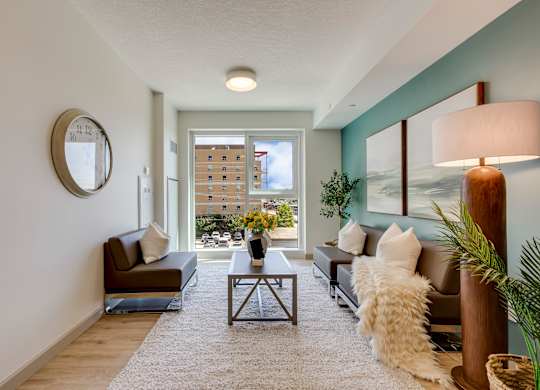 A living room with a brown couch, a coffee table, and a large window.