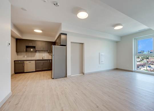 A kitchen with a refrigerator, cabinets, and a window overlooking a cityscape.