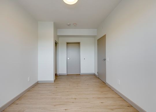 A long, empty hallway with a white door at the end.