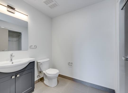 A white toilet is in a small bathroom with a sink and mirror.