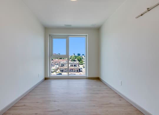 A large empty room with a view of the city through the window.