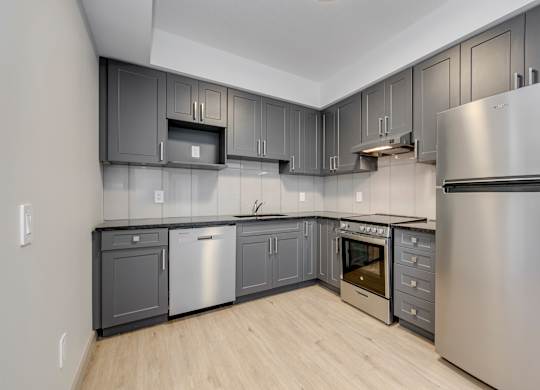 A modern kitchen with stainless steel appliances and wooden flooring.
