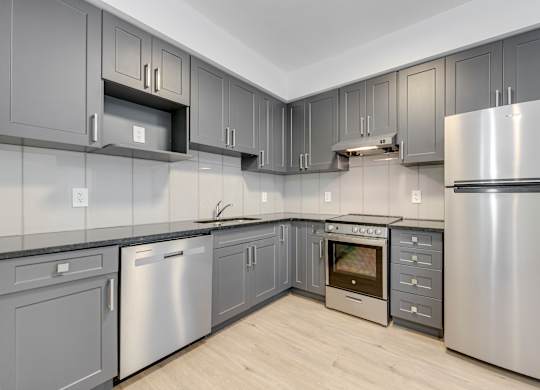 A modern kitchen with stainless steel appliances and grey cabinets.