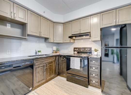 A kitchen with wooden cabinets and a black fridge.
