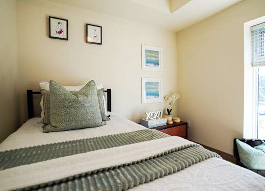 A bed with a green and white striped blanket and a green pillow is in the foreground of the image.